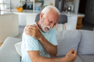 Older man holding his painful shoulder, a common sign of a rotator cuff tear