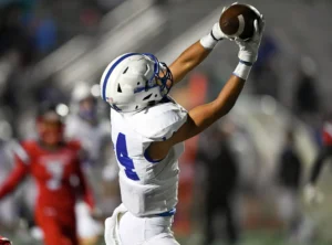 Young football player reaching overhead to catch a pass