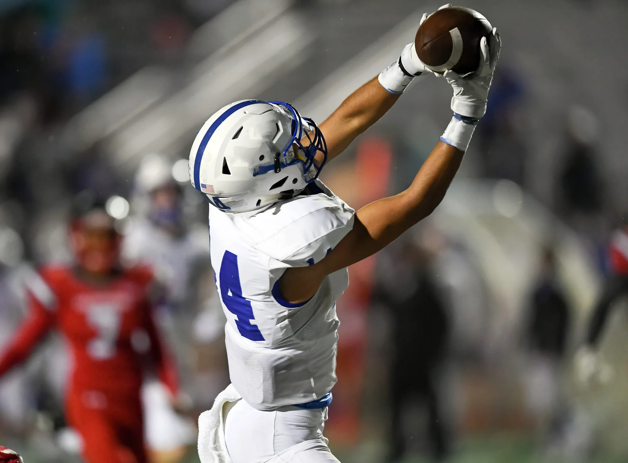 Young football player reaching overhead to catch a pass