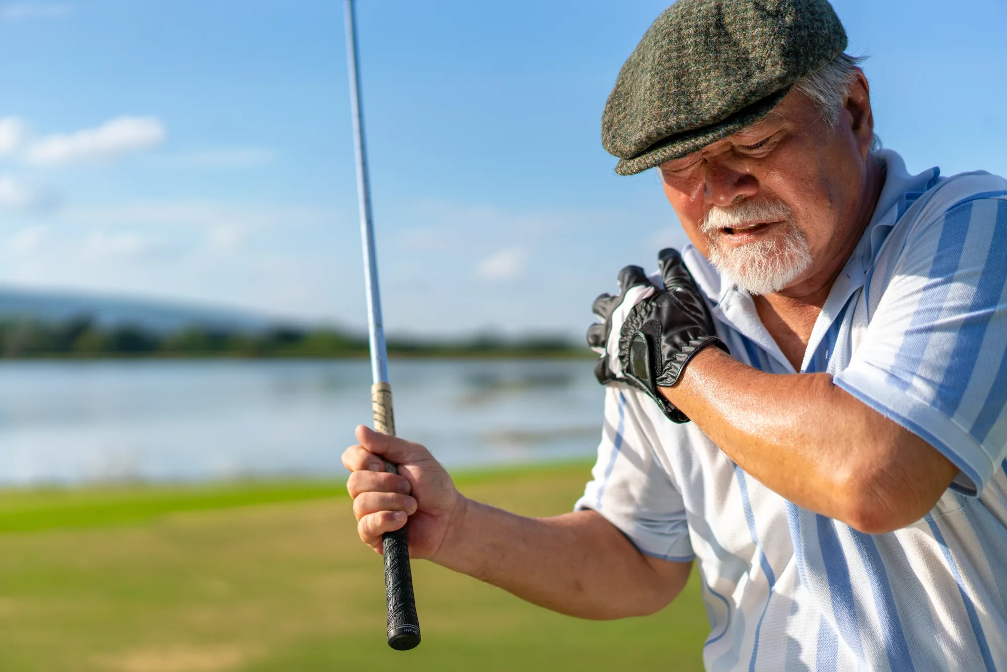 Golfer holding his painful shoulder on the course, a common reason patients ask about shoulder arthroscopy