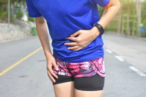 Runner holding her lower abdomen and the front of her hip in pain